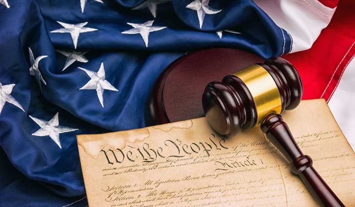 Gavel on U.S. Constitution with American flag background.