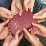 The Bible Held By Several People