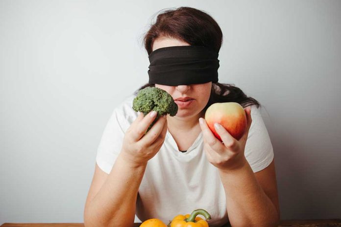 Blindfolded woman holding a fruit and a vegetable