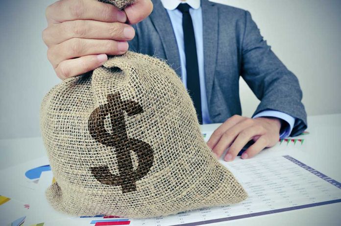 Bag with a dollar sign on it held by a man in a suit