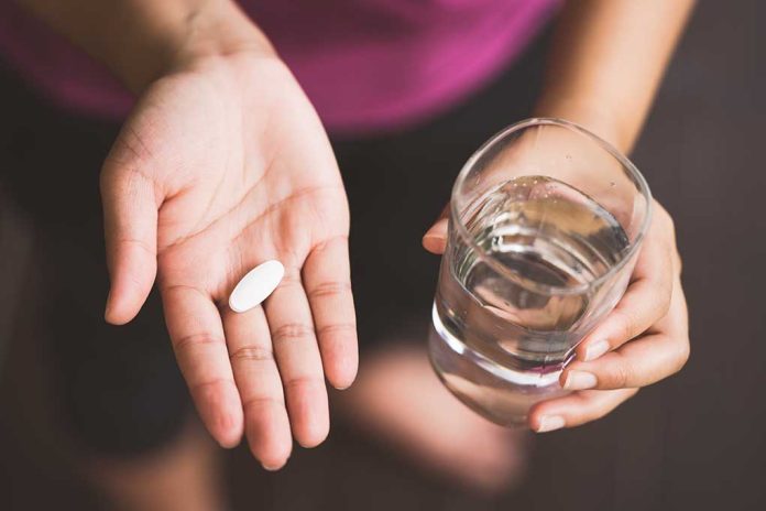 Woman holding a pill and a glass of water