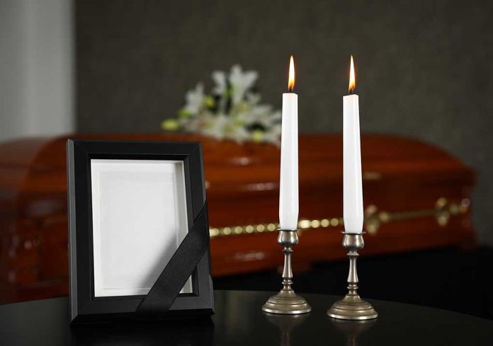 Casket, photo frame, and two lit candles.