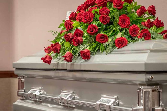 Silver casket with red rose arrangement on top.