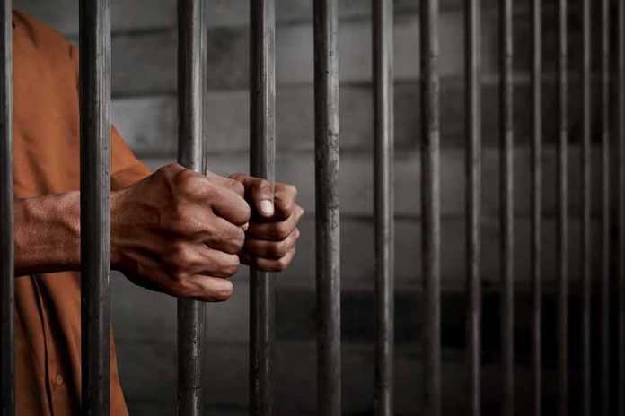 Person gripping metal jail bars tightly