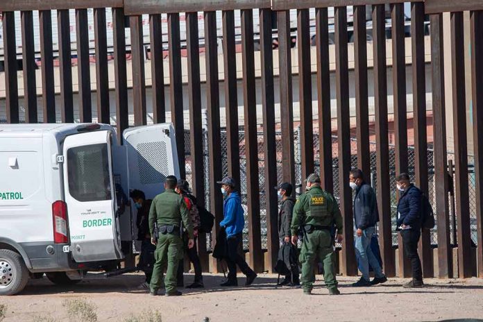 Border patrol agents detaining individuals near a fence