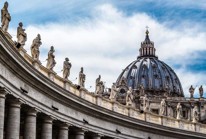 St. Peter's Basilica dome with statues and clouds.