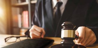 Gavel judges hand glasses and book on desk
