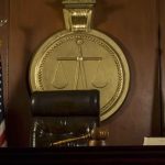 Judge's chair, gavel, flags, and scales of justice emblem