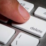 Finger pressing a delete key on keyboard