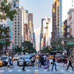 Busy city intersection with people and cars.