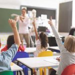 Children raising hands in classroom