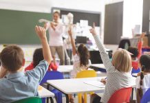 Children raising hands in classroom