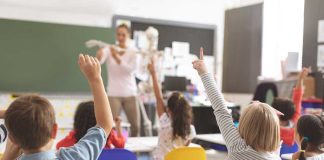 Children raising hands in classroom
