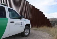 Border protection vehicle near a large metal fence