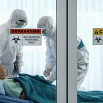 Healthcare workers in protective gear in quarantine room