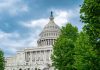 US Capitol building with trees and cloudy sky
