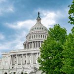 US Capitol building with trees and cloudy sky