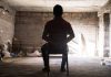 Person tied to chair in a dimly lit room
