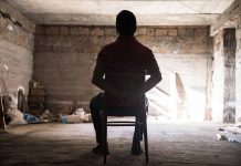 Person tied to chair in a dimly lit room