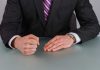 Person in suit with clenched fist on table