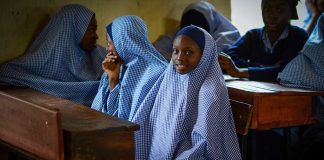 Girls in checkered hijabs sitting at school desks