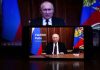 Man speaking on screen with Russian flag background