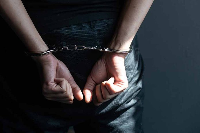 2182647107 featured image Hands in handcuffs behind back in dark room.