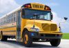 Yellow school bus parked on pavement under blue sky
