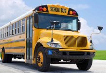 Yellow school bus parked on pavement under blue sky