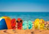 Colorful beach ball flip flops sand sea background