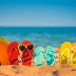Colorful beach ball flip flops sand sea background
