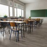 Empty classroom with desks chairs windows and chalkboard