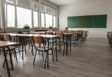 Empty classroom with desks chairs windows and chalkboard