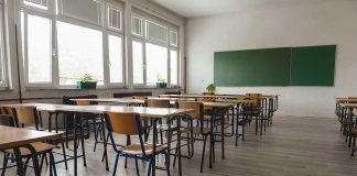 Empty classroom with desks chairs windows and chalkboard