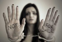 Handcuffed woman shows NOT FOR SALE on her palms