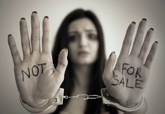 Handcuffed woman shows NOT FOR SALE on her palms