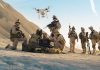 Military personnel operating drone in desert area