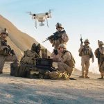 Military personnel operating drone in desert area
