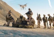 Military personnel operating drone in desert area