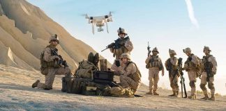 Military personnel operating drone in desert area