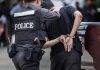 Police officer arrests handcuffed person