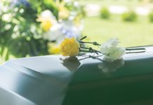 Yellow and white flowers on polished green casket