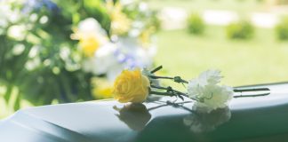 Yellow and white flowers on polished green casket