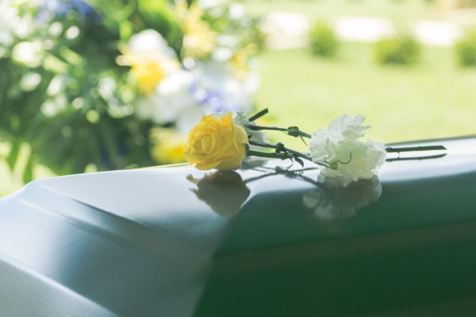 1014454810 featured image Yellow and white flowers on polished green casket