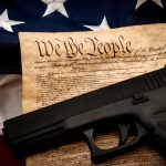 Gun on US Constitution and American flag