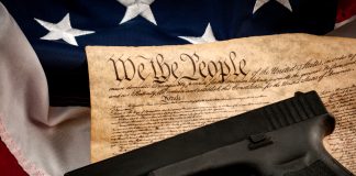 Gun on US Constitution and American flag