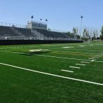 Empty football field with bleachers in background