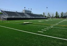 Empty football field with bleachers in background
