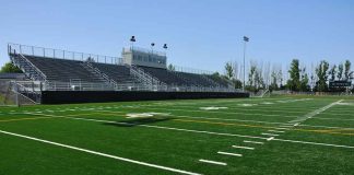Empty football field with bleachers in background