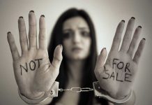 Handcuffed woman shows NOT FOR SALE on her palms